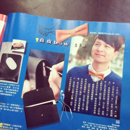 A magazine page featuring a man wearing an orange bow tie, with text in Chinese and images of leather accessories, including a mouse pad, a phone case, and a wallet.